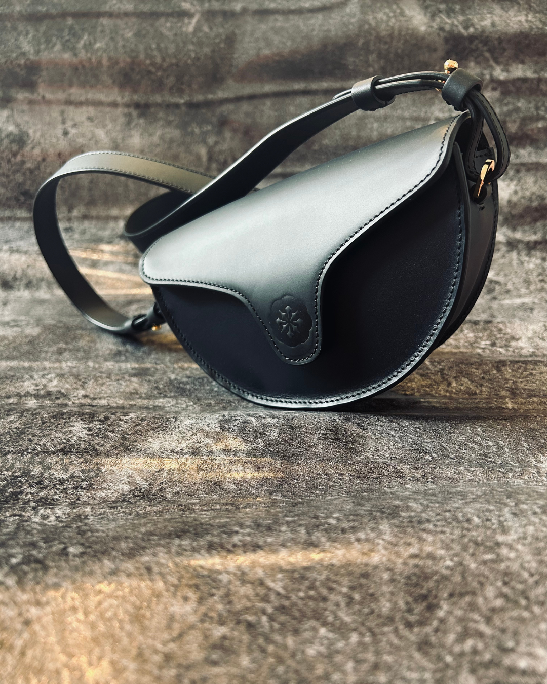 CNicol Black Leather Lily Mini Bag on a textured grey carpet