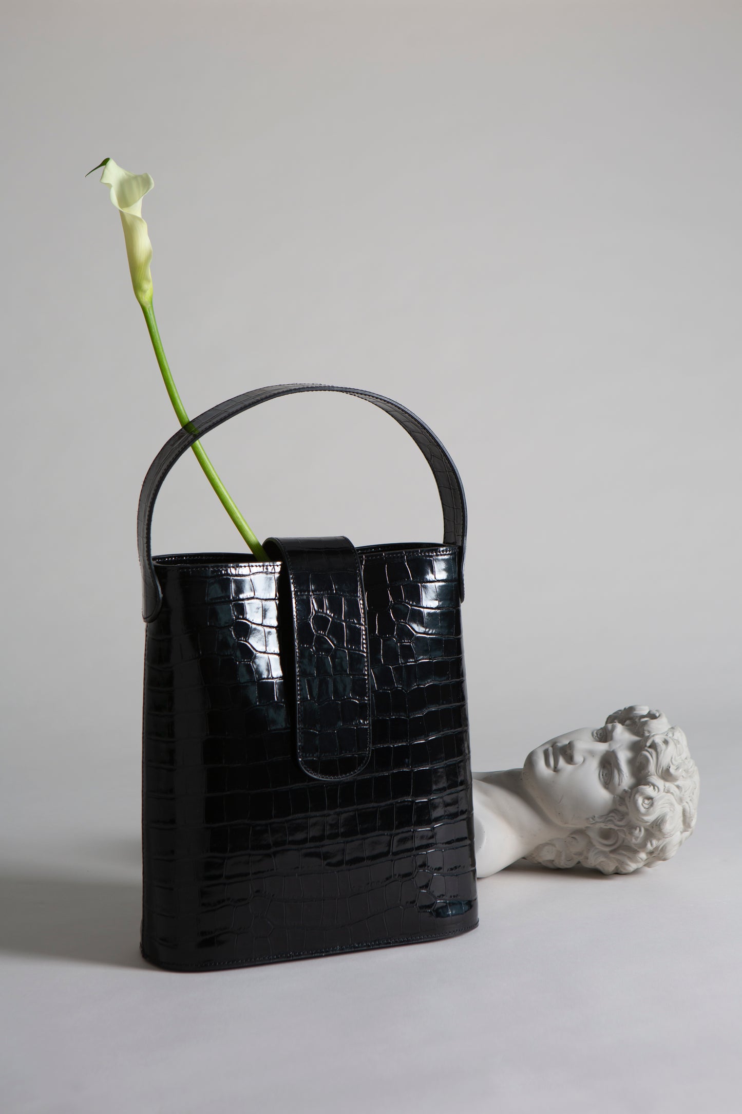 CNicol Black Croc Leather Holly Maxi Bag in front of Marble Statue Bust on its Side with Single Flower Inside