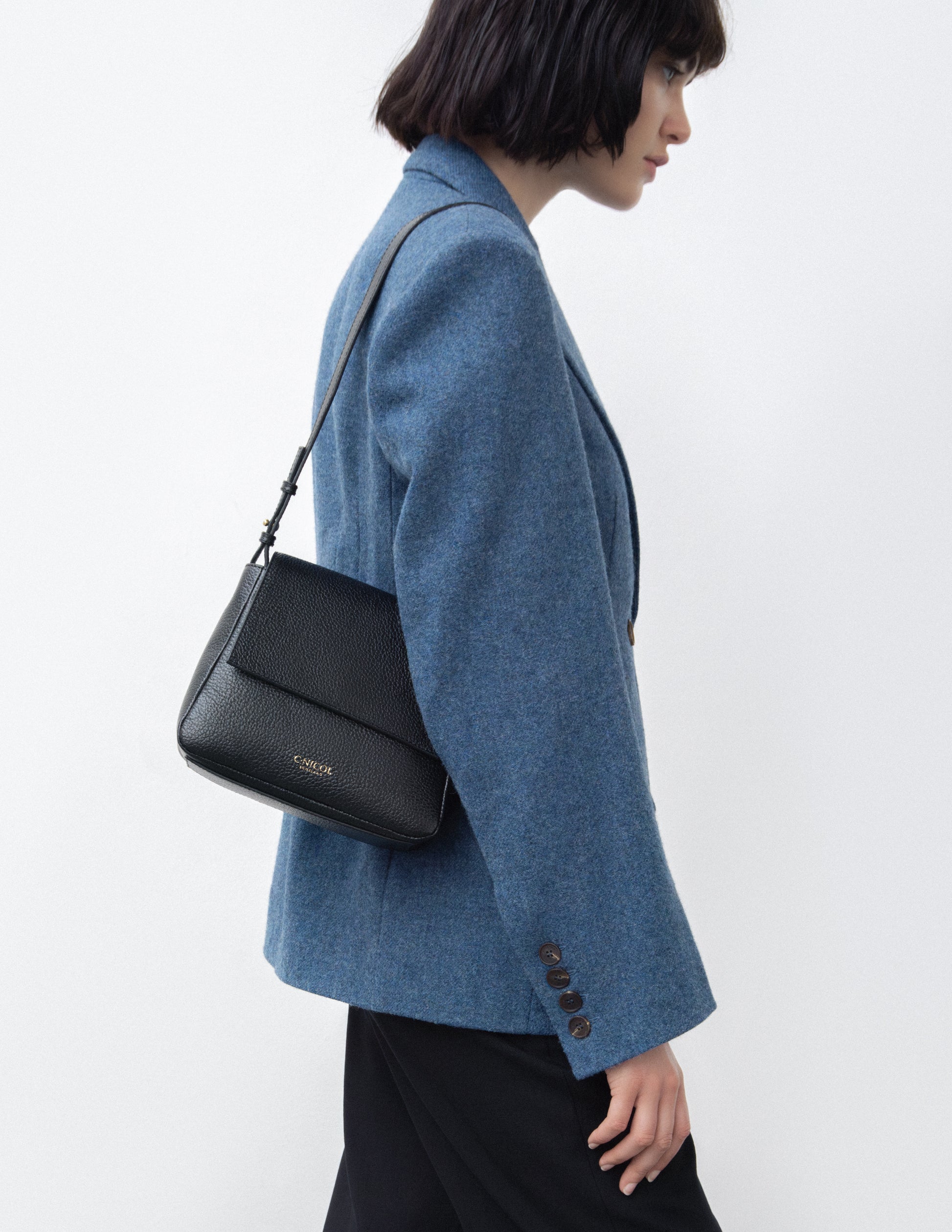 CNicol Black Leather Bag worn by model facing sideways in a blue blazer and black trousers
