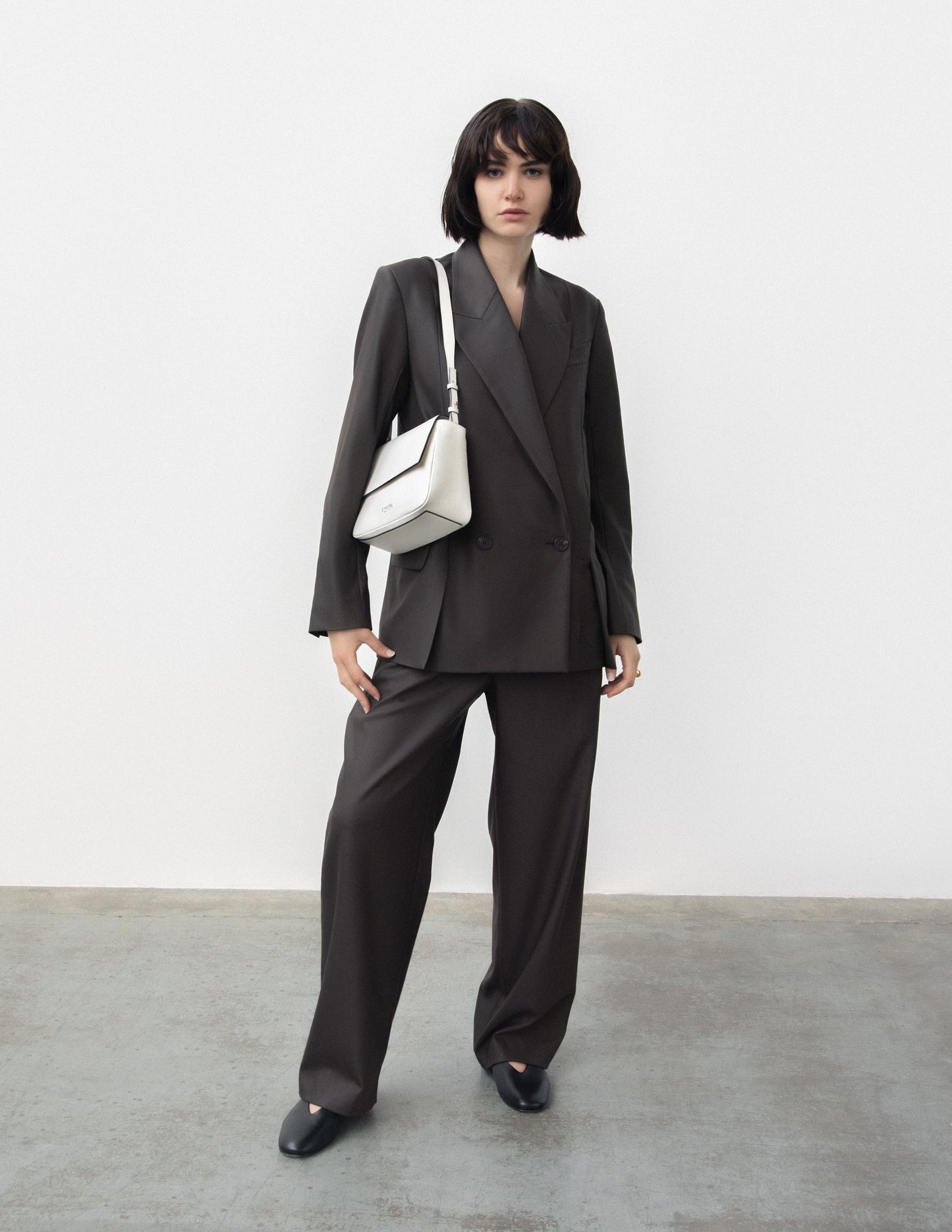 CNicol White Leather Fia Bag with Model in all black suit