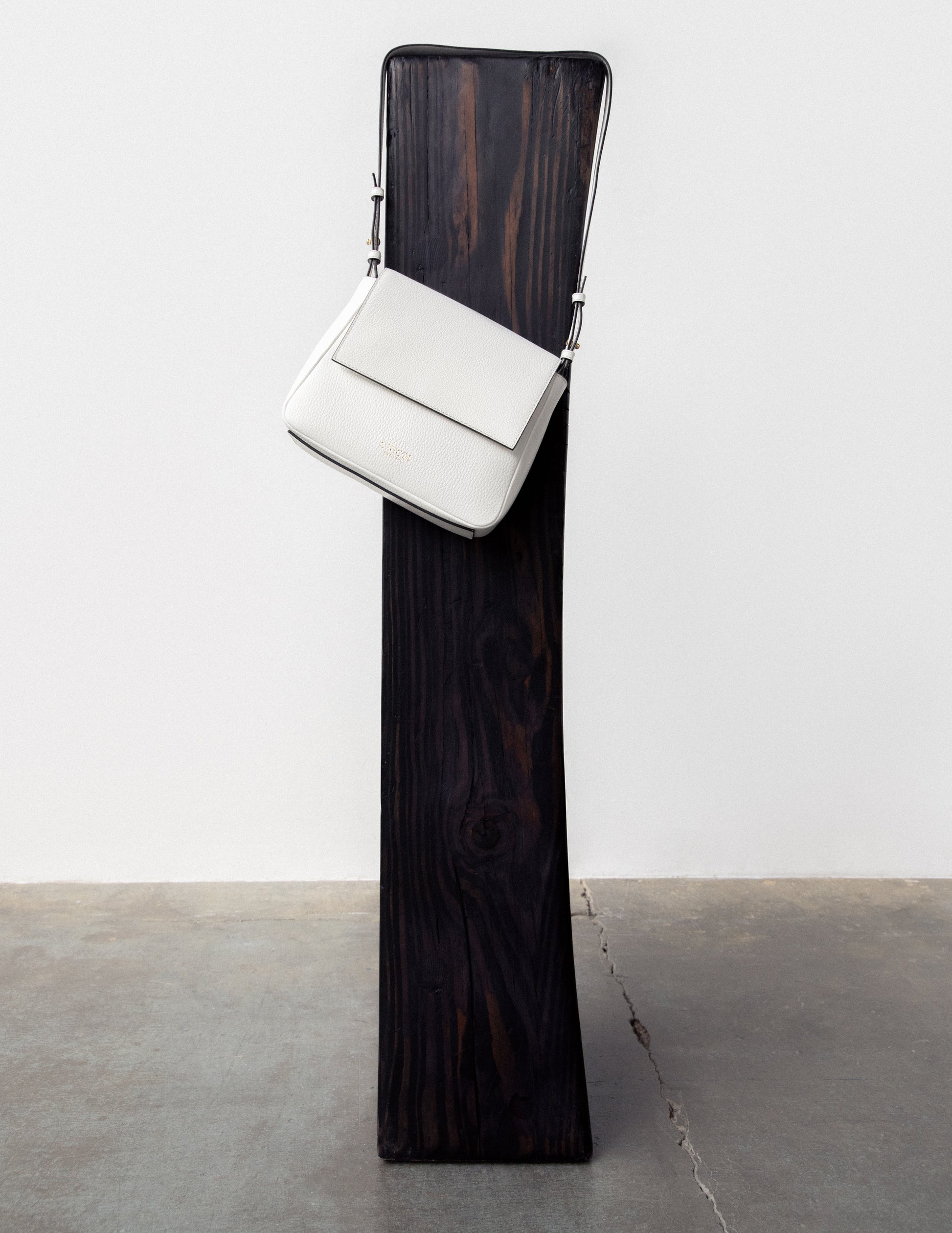 CNicol White Leather bag hanging from a Dark Brown Pedestal