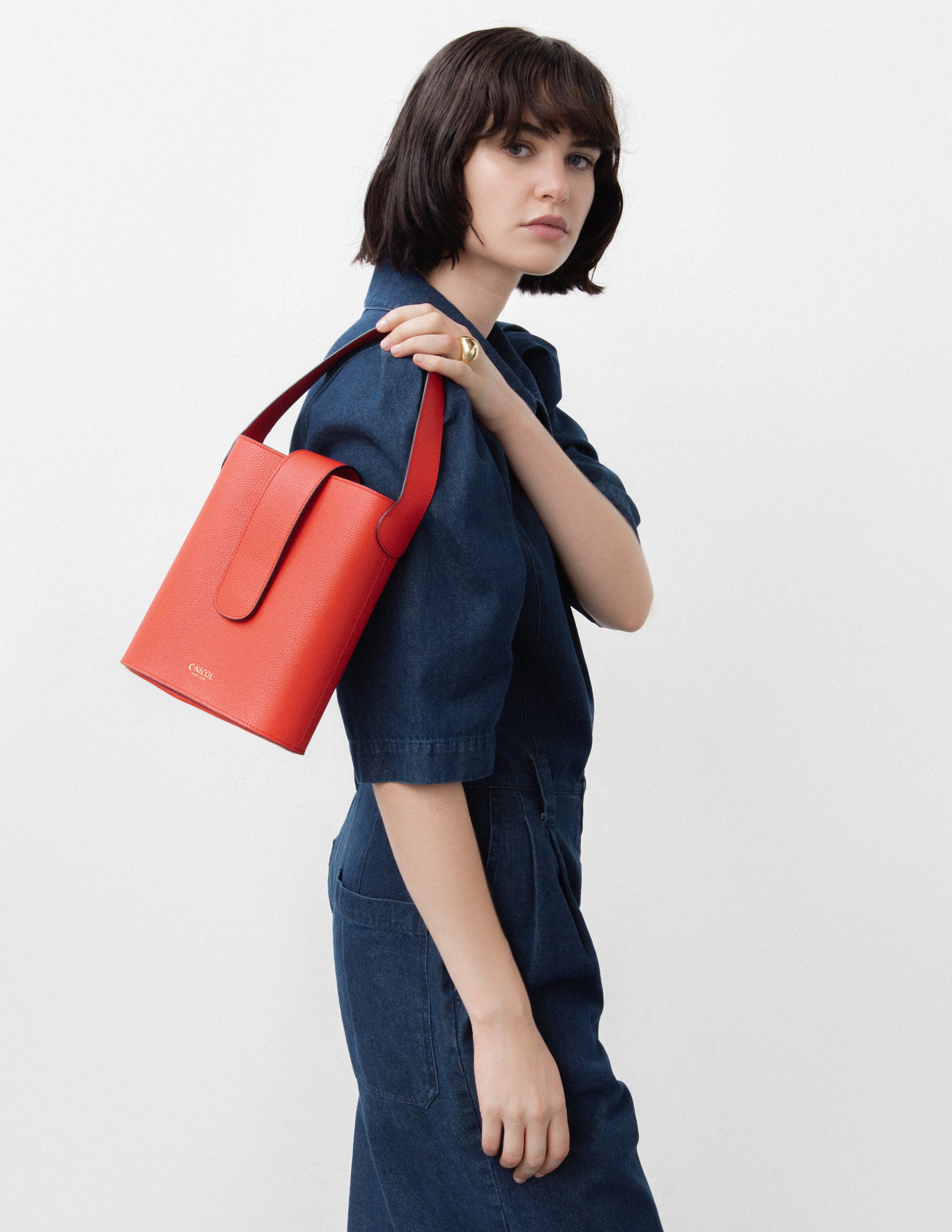 CNicol Red Leather Bag held by model wearing a navy blue jumpsuit with the bag slung over her right shoulder