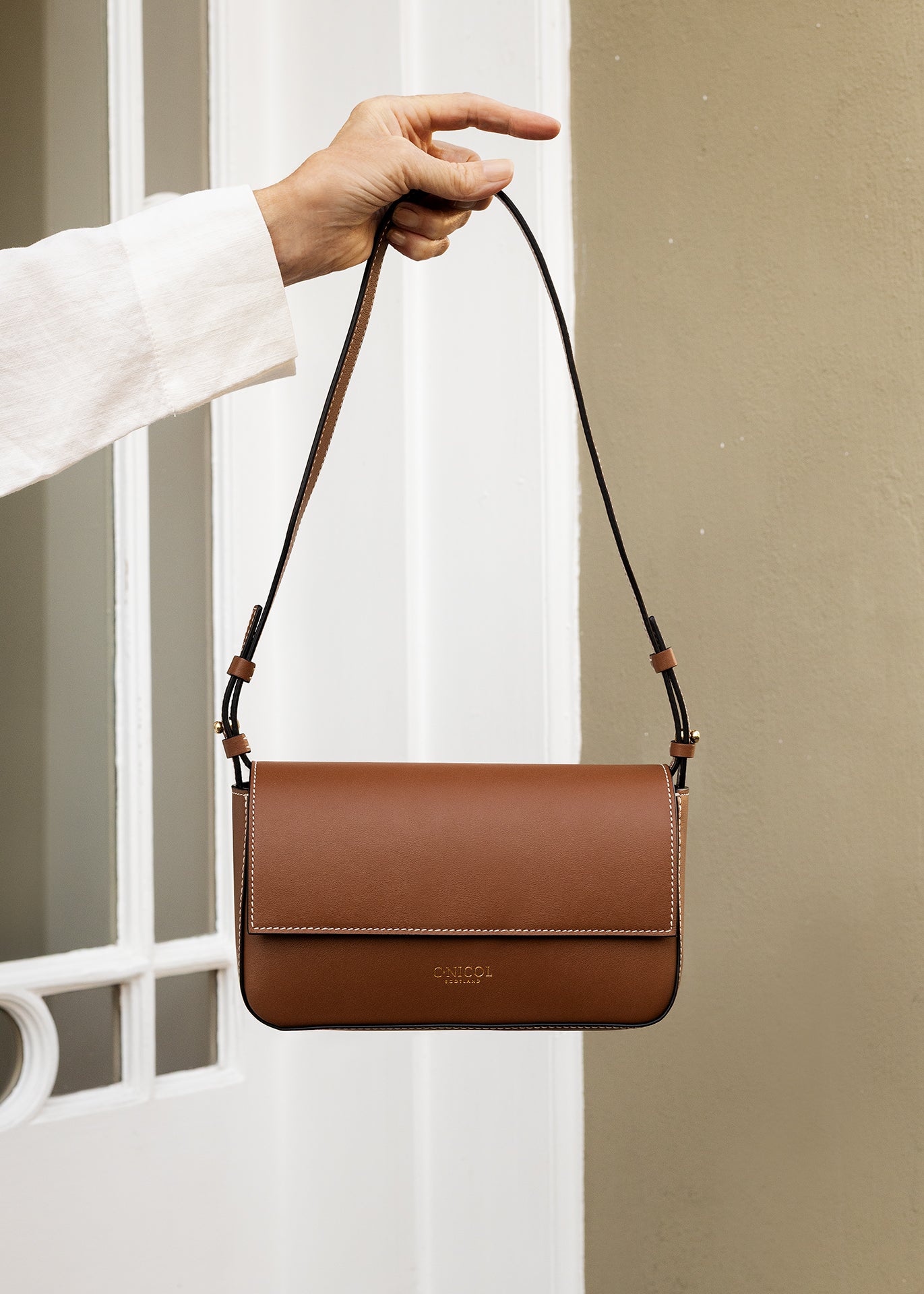 C.Nicol Scotland tan leather bag front view, held out my a woman's arm